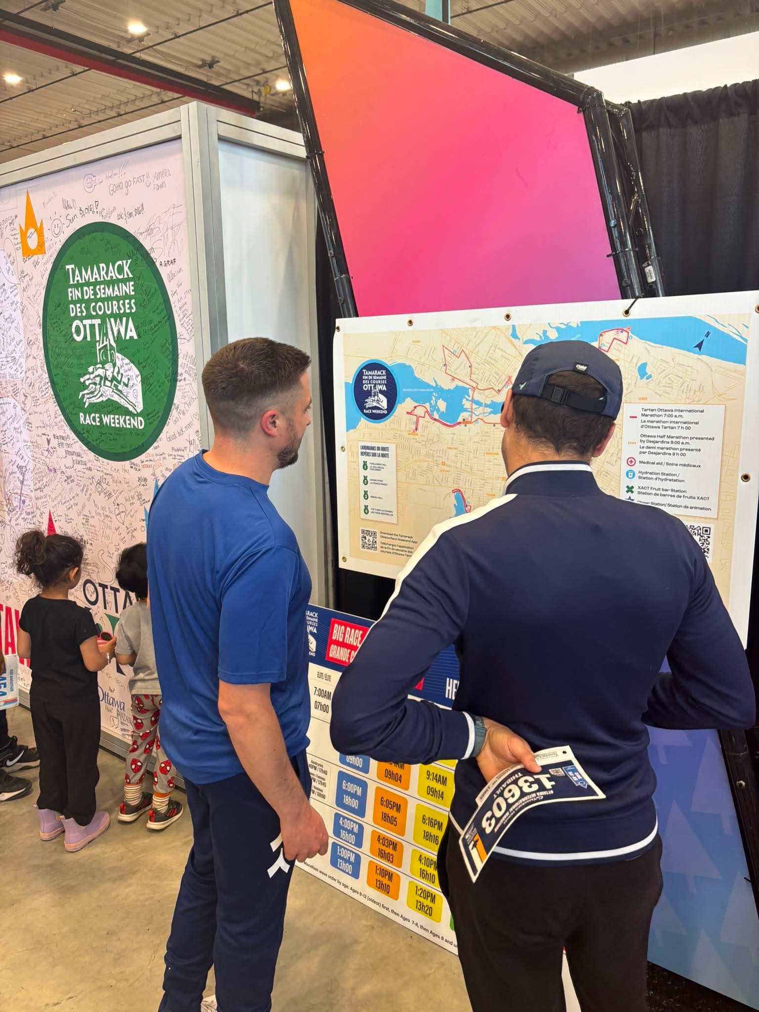Retrait des dossards — Tamarack Ottawa Race Weekend 2026 Participants The Run Away consultant le parcours du marathon au salon des coureurs du Tamarack Ottawa Race Weekend 2026